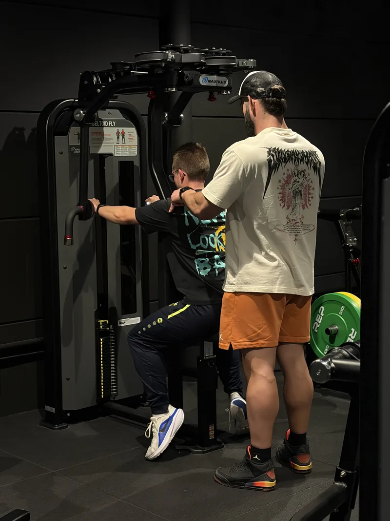 Dimitri Oeyen corrigeert de schouderpositie van een klant op de deltoid fly tijdens personal training in Route27